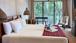 A bedroom with a bed, a ceiling fan, a window with curtains, a chair, and a small table.