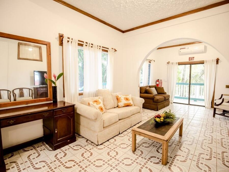 A hotel lobby with a sofa, a coffee table with flowers, a desk, and an archway leading to an exit.
