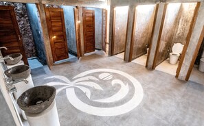 A public restroom with multiple stalls, a central decorative floor pattern, and a sink area with stone basins.