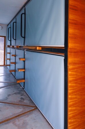 A corridor with blue walls and wooden doors, leading to a room with a large window.
