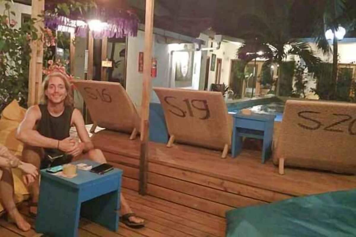 A wooden deck with seating areas marked with numbers, a small table, and a pool in the background.