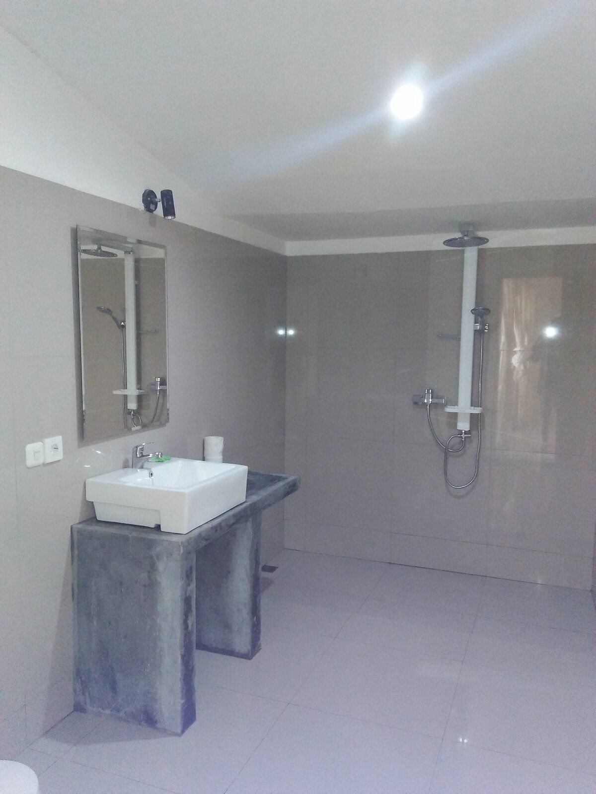 A modern bathroom with a large mirror, a pedestal sink, a shower, and a vanity.