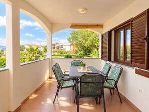 Een balkon met een tafel en stoelen, uitkijkend op een woonwijk met huizen en bomen.