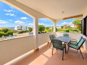 Een balkon met een tafel en stoelen, een uitzicht op de omgeving en een heldere lucht.