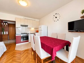 A compact living space with a dining area, kitchenette, and a TV mounted on the wall. - Apartment Zdenka with three bedrooms (Njivice)