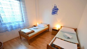 A room with two wooden beds, a window with sheer curtains, and a wall decal of a ship. - Apartment Zdenka with three bedrooms (Njivice)