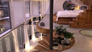 Un interior moderno con una escalera de caracol, una cama con dosel y vistas al exterior.
