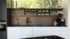 Una cocina moderna con horno empotrado, cafetera y ventana con vistas a zonas verdes.