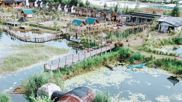 Zona residencial con casas, un pequeño estanque y un jardín con mobiliario.