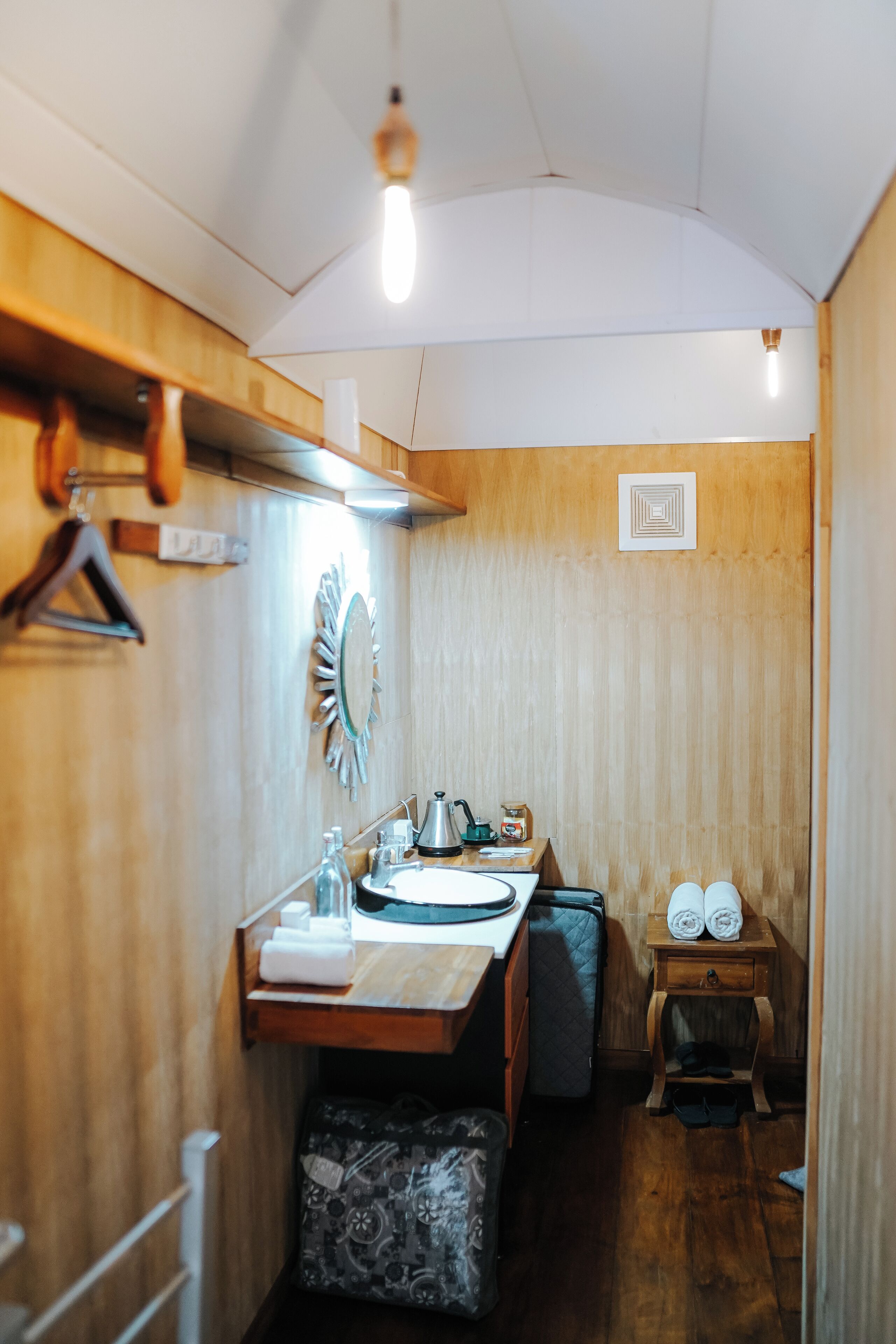 Un baño pequeño y acogedor, con muebles de madera, un lavamanos, espejo, toallero y un mueble de madera.