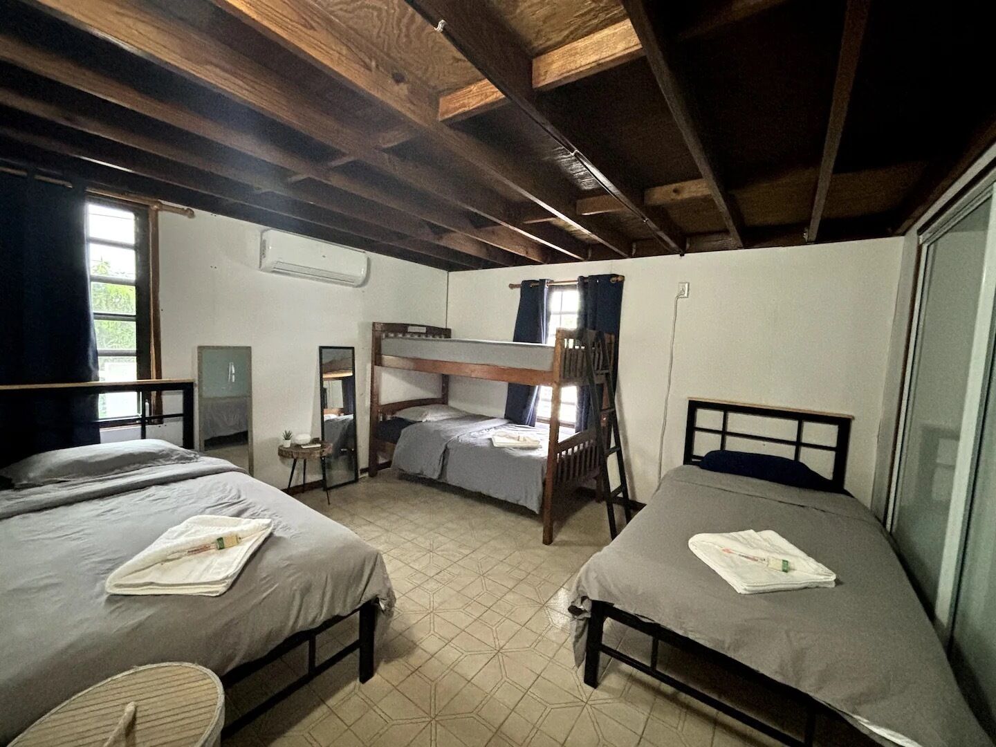 Un dormitorio con tres literas, una mesita con espejo y una ventana con cortinas.