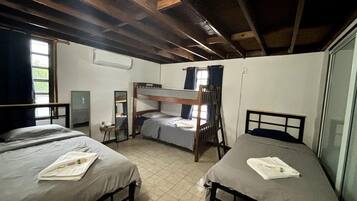 Un dormitorio con tres literas, una mesita con espejo y una ventana con cortinas.