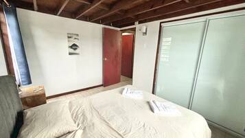 A hotel room with a bed, a wardrobe, and a door.