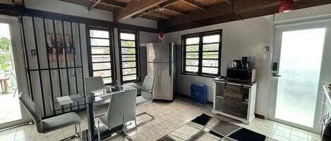 A spacious kitchen with a dining area, large windows, and a tiled floor.