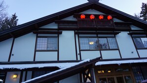 A traditional building with a sloped roof, wooden balcony, and multiple windows. - Tokiwatei (Hakuba)