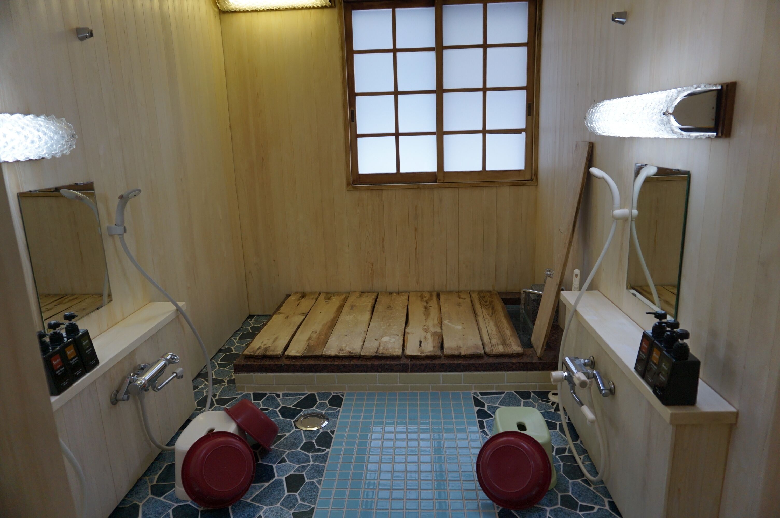 A traditional Japanese-style bathroom with a wooden floor, a small window, and a wooden bench.