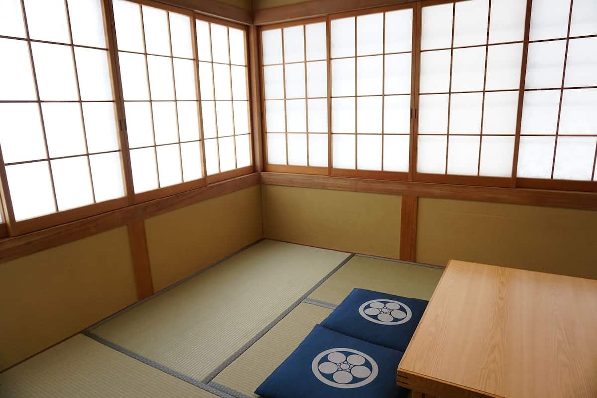 A traditional Japanese room with tatami flooring, shoji screens, and a low wooden table.