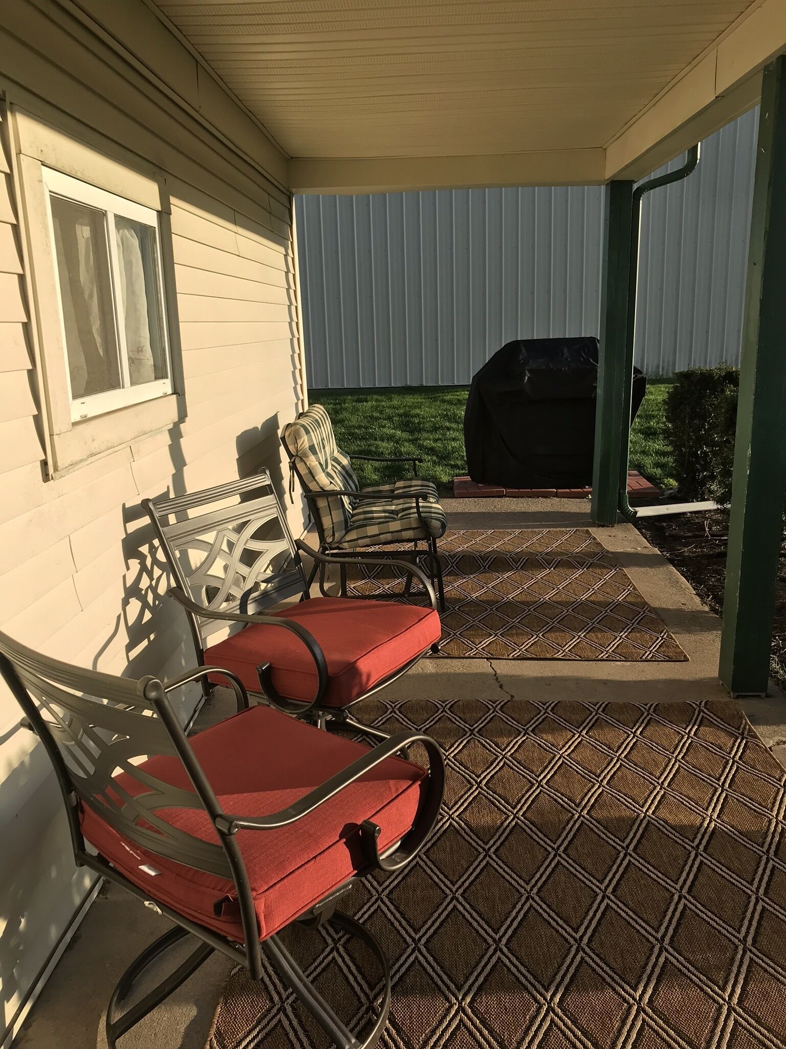 En täckt uteplats med utemöbler och en grill.