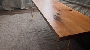 Huoneessa on puinen pöytä, sänky, ikkuna, jossa on verhot, ja ilmastointilaite.