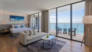 Une chambre d’hôtel moderne dotée d’un grand lit, d’un canapé, d’une petite table et d’un balcon offrant une vue sur la mer.