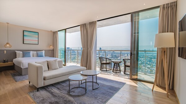 A modern hotel room with a large bed, a sofa, two small tables, and a balcony with a city view. - Prince Hotel Da Nang  (Da Nang)