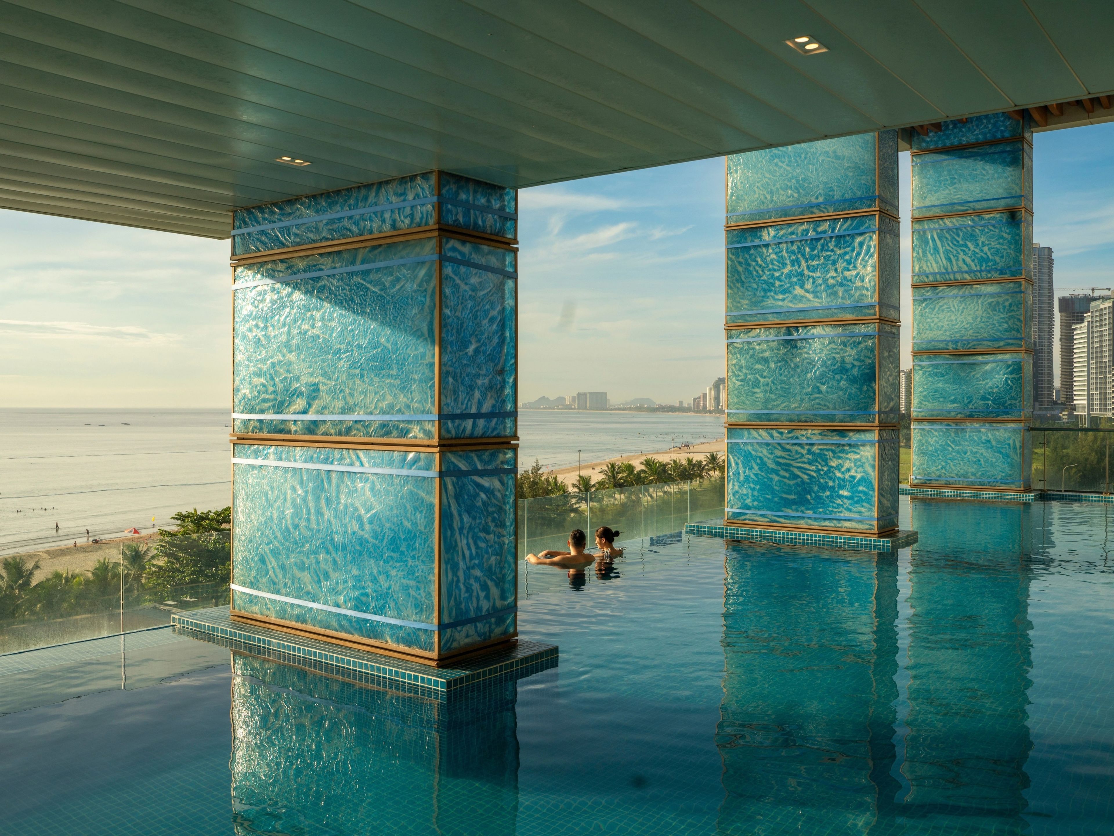 An infinity pool with a view of the beach and city skyline.