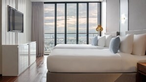 A modern hotel room with a large bed, a TV mounted on the wall, and a city view through large windows. - Prince Hotel Da Nang  (Da Nang)