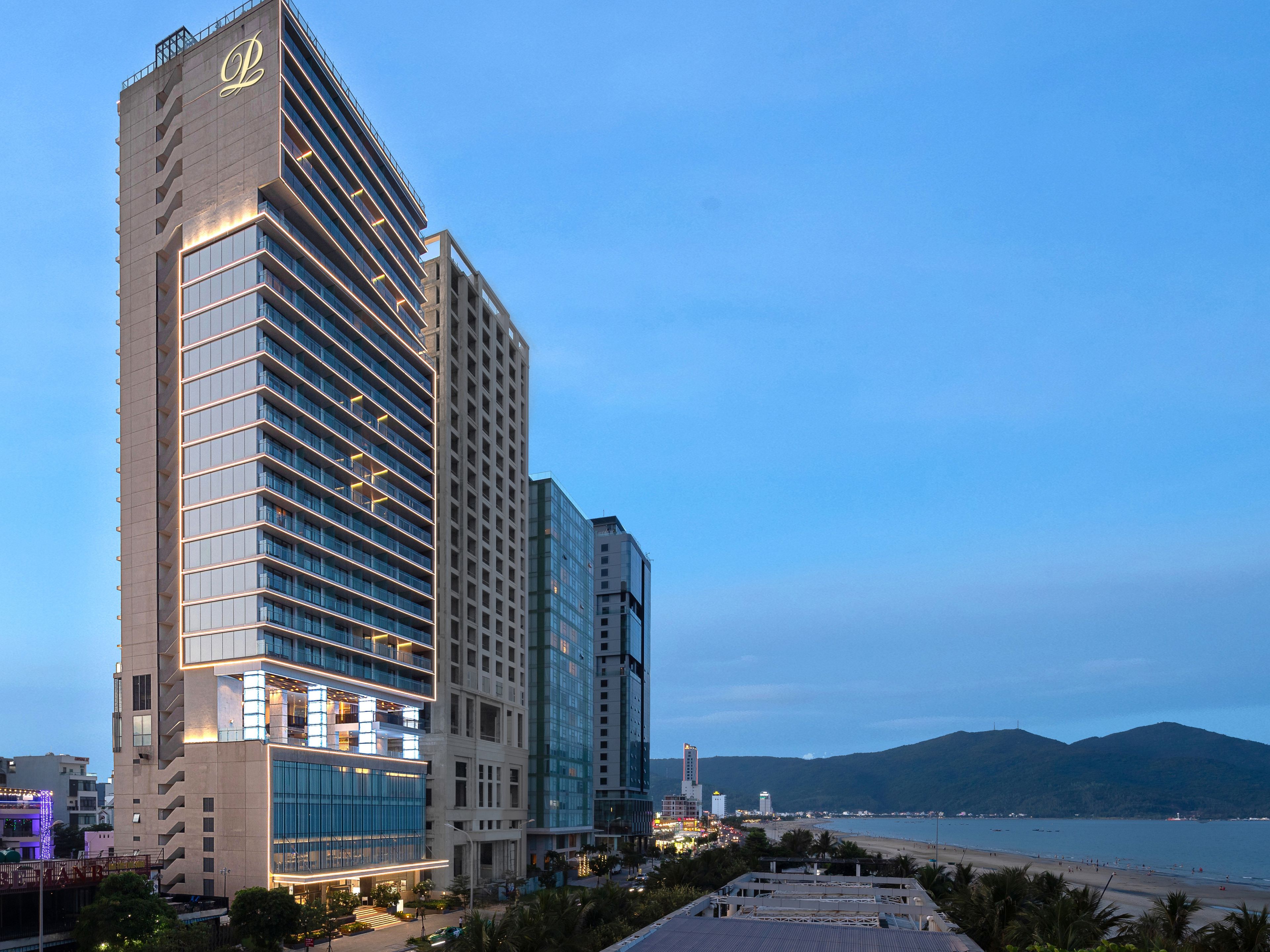 A high-rise hotel with multiple floors, large windows, and a prominent logo on the facade.