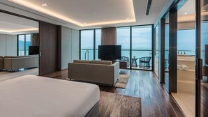 A modern hotel room with a large bed, a sofa, a TV, and a balcony with a view of the sea. - Prince Hotel Da Nang  (Da Nang)