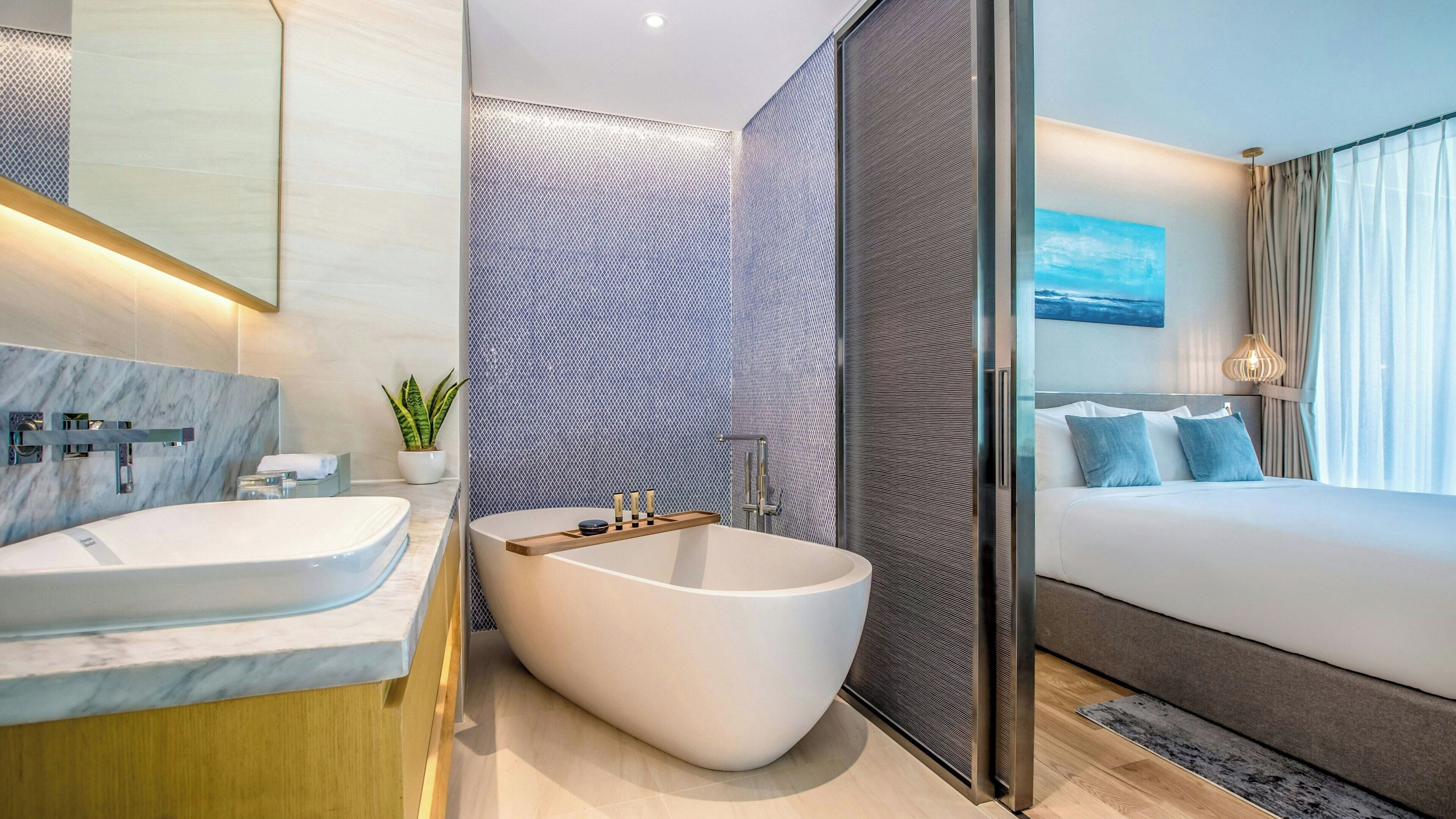 Un baño moderno con una bañera independiente, un espejo grande y una planta en maceta.
