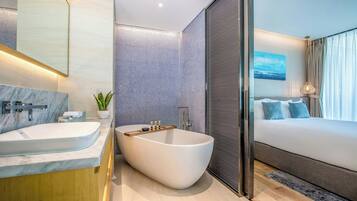 Un baño moderno con una bañera independiente, un espejo grande y una planta en maceta.