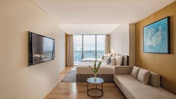 A modern living room with a large window, a sofa, a coffee table, and a TV.