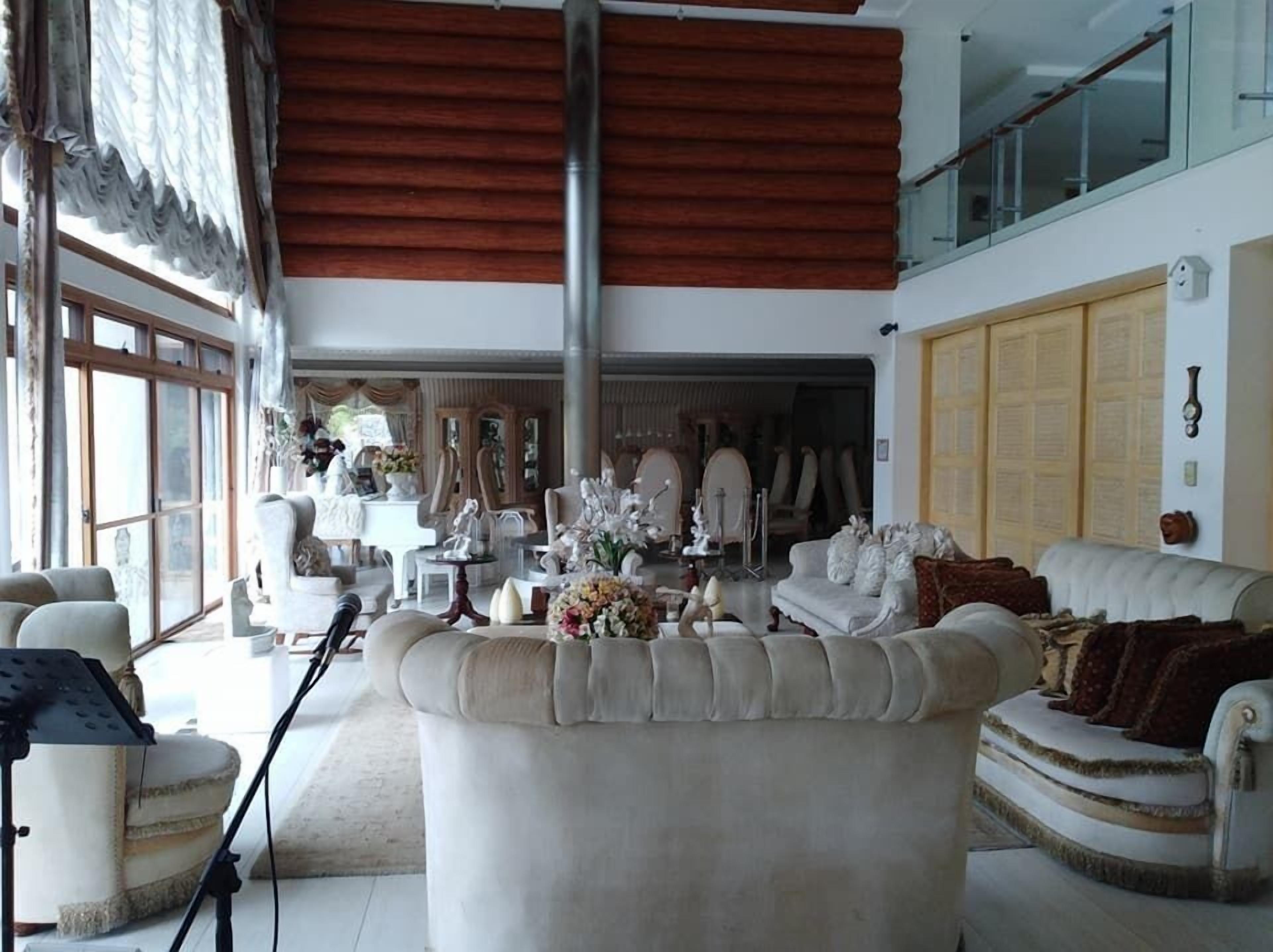 Een ruime woonkamer met een hoge plafond, grote ramen en uitzicht op het interieur.