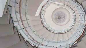 Una escalera de caracol con un espacio abierto en el centro, rodeada de barandillas de cristal.