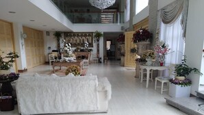 Un amplio espacio de sala con un sofá blanco, una mesa de comedor con sillas y una araña.
