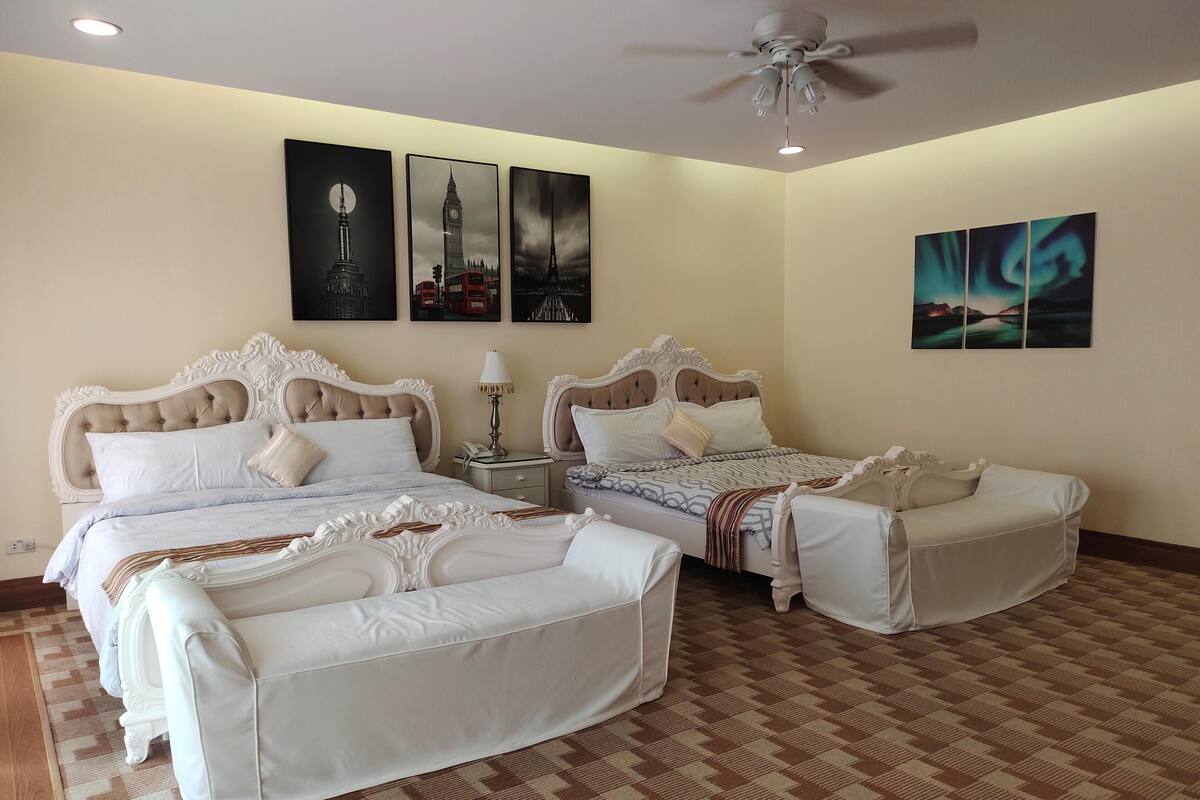 A hotel room with two beds, a ceiling fan, and artwork on the walls.