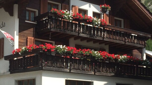 A multi-story building with balconies adorned with flower boxes. - Miranda by Interhome (Saas-Almagell)