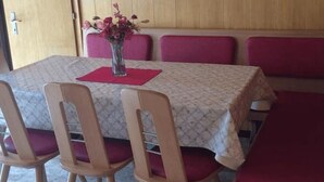 A dining area with a table set for four, surrounded by wooden chairs with red cushions. - Miranda by Interhome (Saas-Almagell)