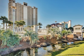 A hotel with a large building, a small pond, and palm trees.