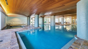 A large indoor swimming pool with a wooden ceiling and tiled walls.