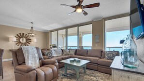 A living room with a sectional sofa, a coffee table, and a ceiling fan.