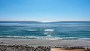 A beach with a clear sky, calm sea, and a sandy shore.