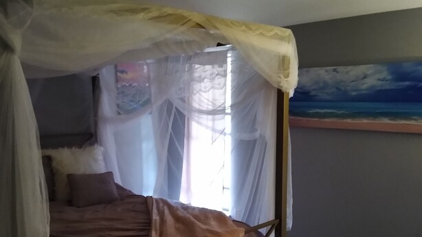Een slaapkamer met een hemelbed, een schilderij aan de muur en een vloerbedekking.