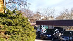 Een parkeerplaats met meerdere auto's, een gazon en een gebouw met een bruin dak.