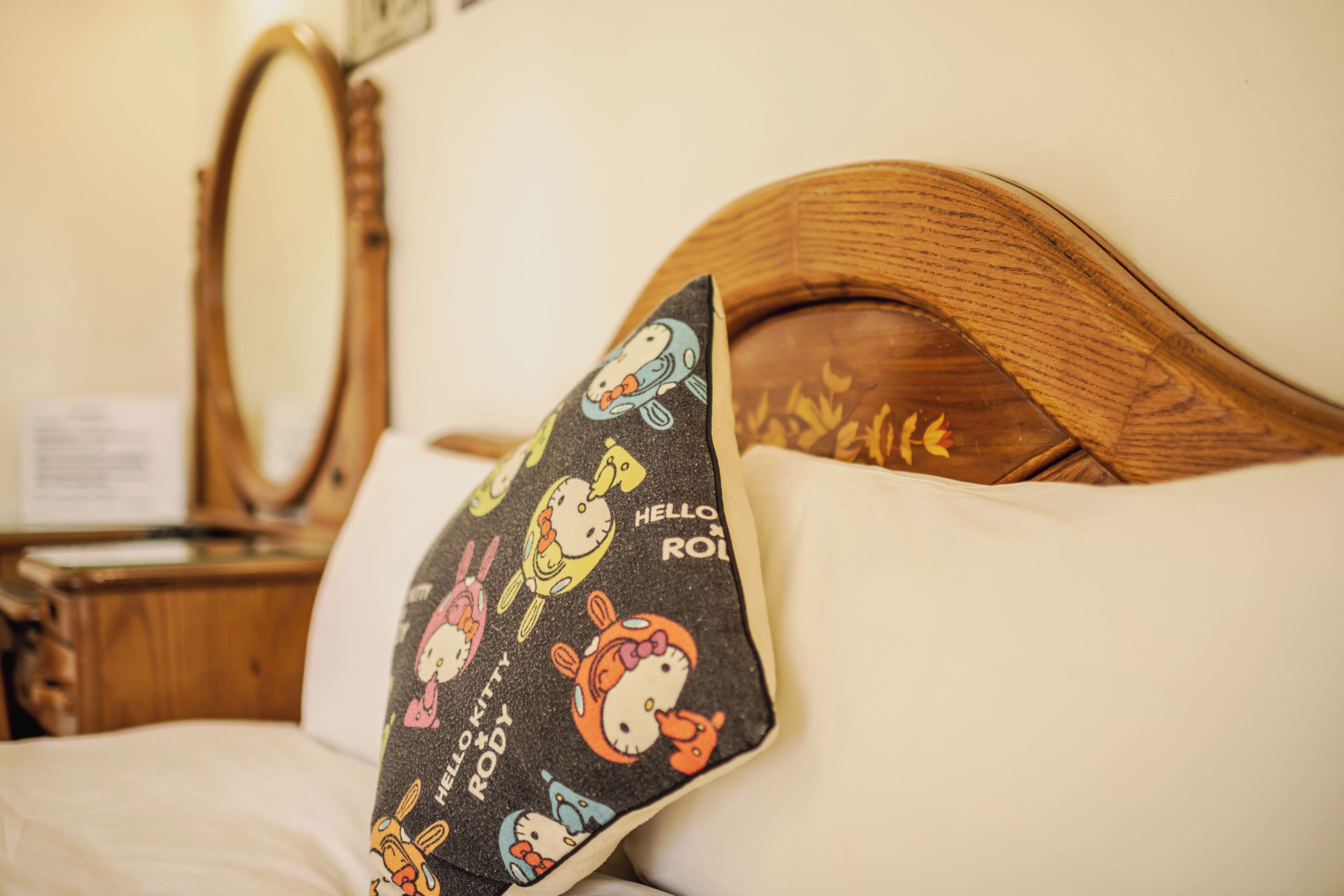 A bed with a pillow featuring Hello Kitty designs.