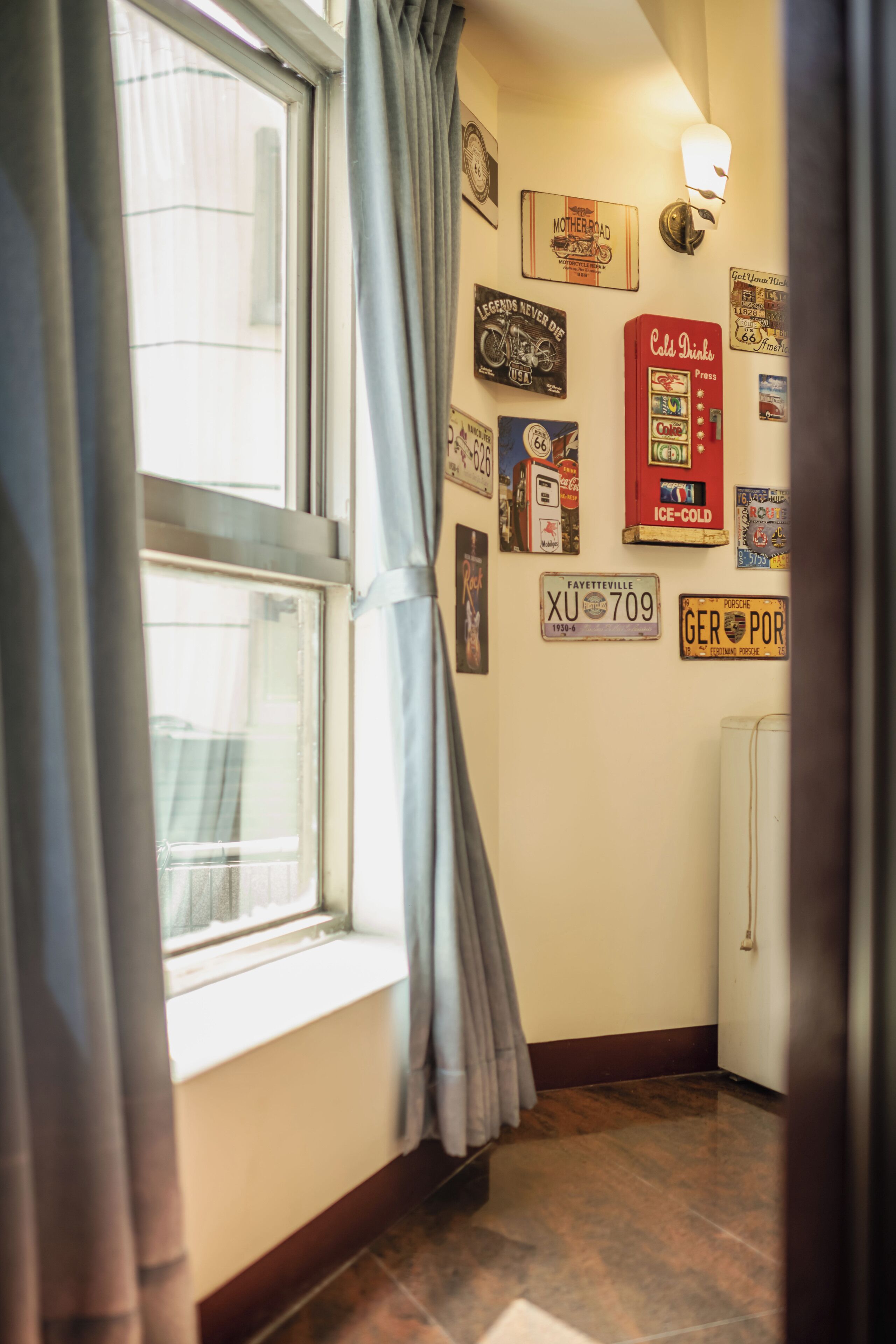 A hallway with a window, curtains, and a wall adorned with various memorabilia and signs.