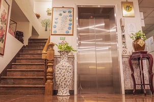 Una escalera que conduce a un ascensor, con un jarrón floral y una mesa decorativa cerca.