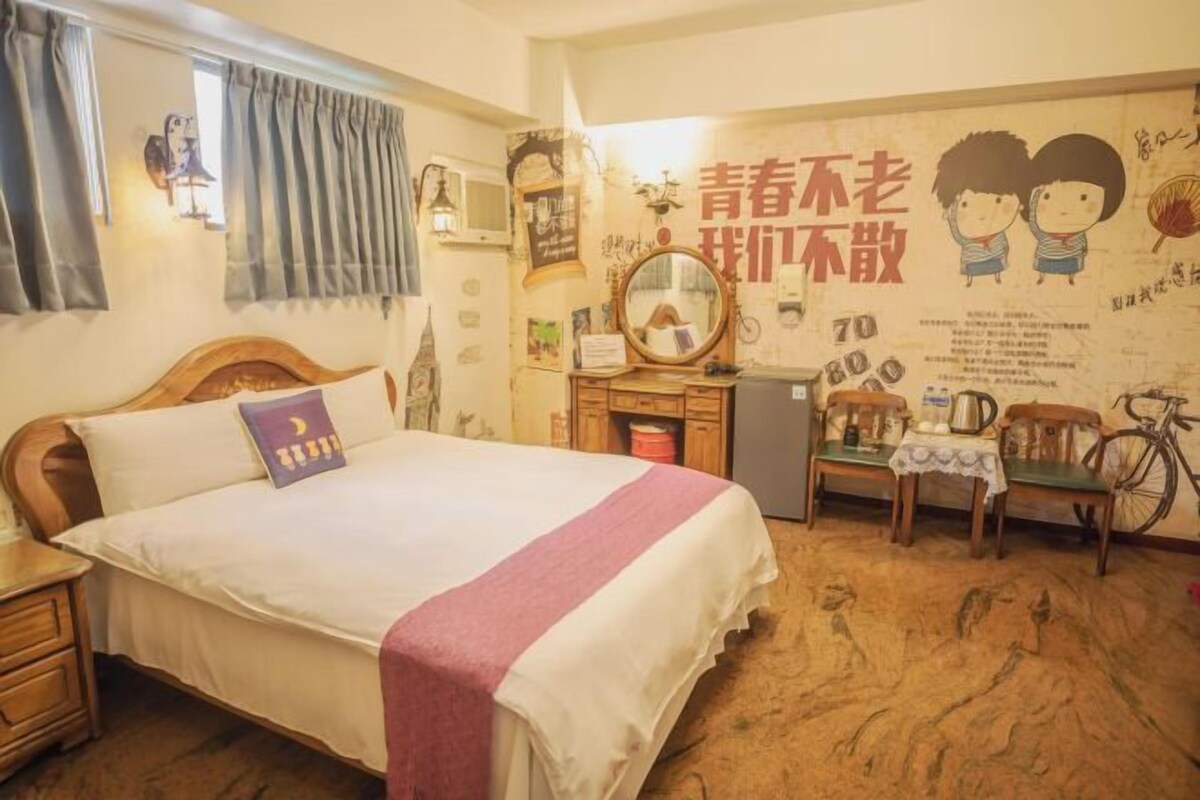 Una camera da letto con un letto, una cassettiera, uno specchio, una bicicletta e una parete decorata.