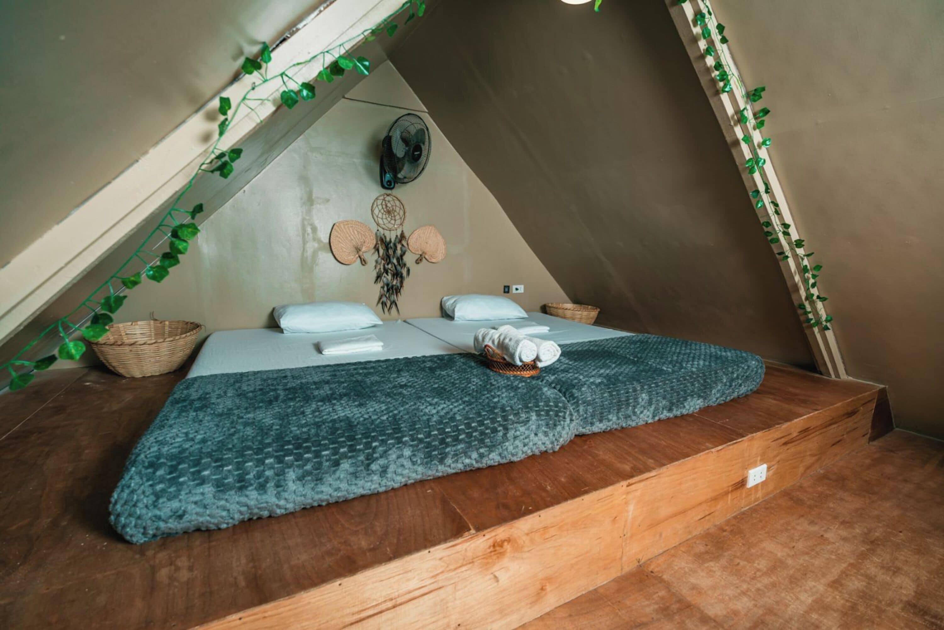A cozy attic bedroom with a bed, pillows, a blanket, and a dreamcatcher on the wall.