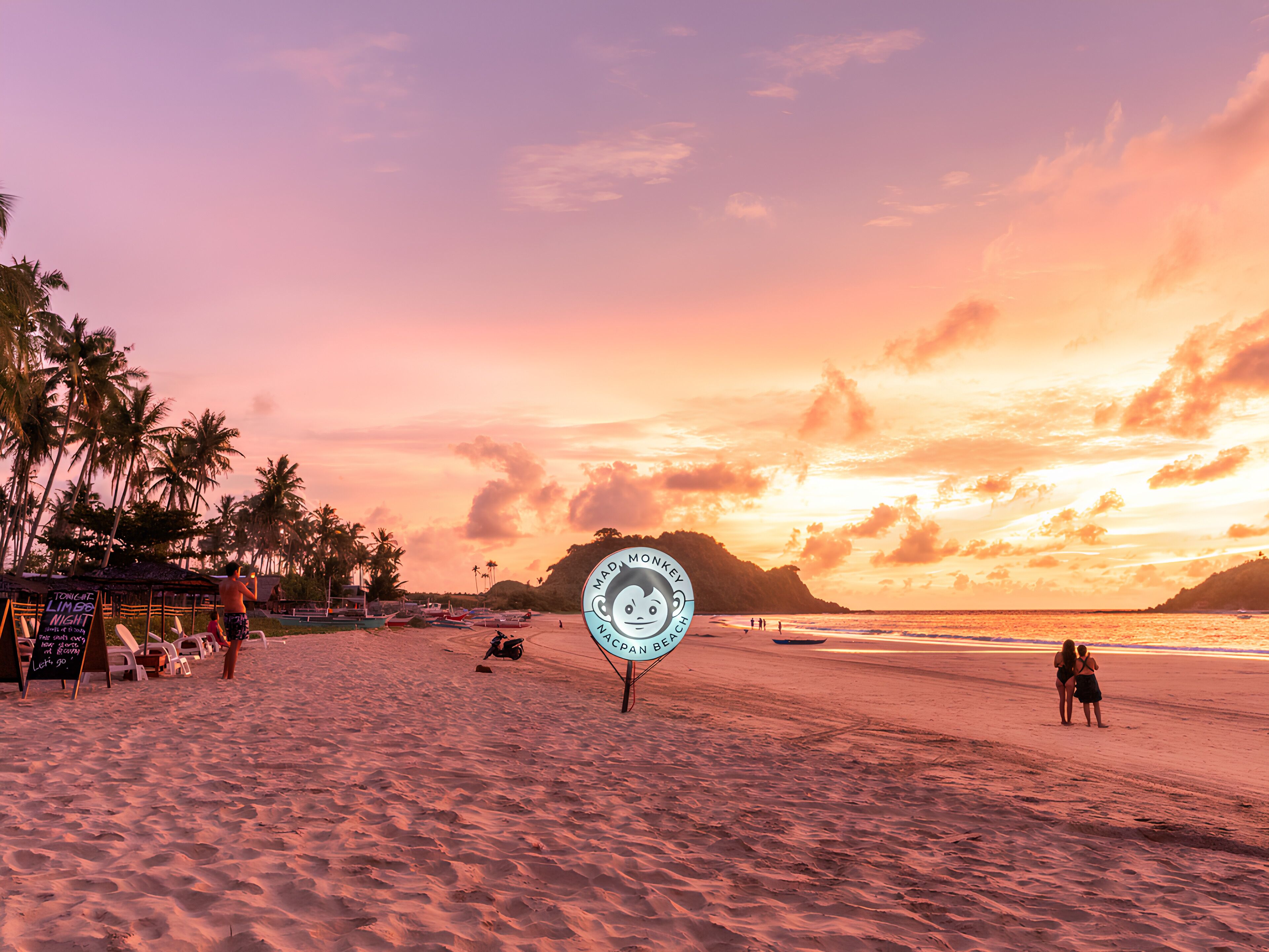 Escena de playa con palmeras, un cartel y un atardecer.